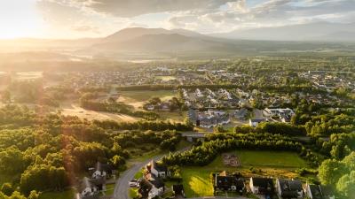 An aerial view of the town of Aviemore with sun peaking over a distant mountain