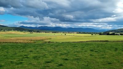Lowland fields with mountains in the distance.