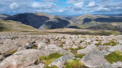 View over boulders across mountain plateau in patchy sunlight
