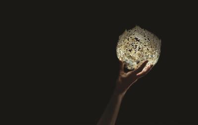 A hand holding a round white sculpture.