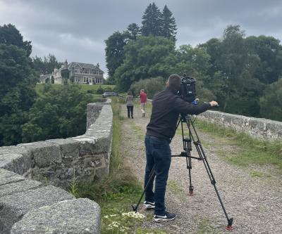 a camera operator filming two people walking over a bridge