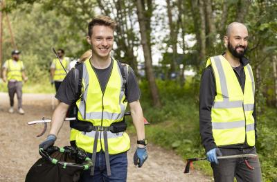 A group of people in hi-vis litter picking on a path in the woods.