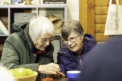 Two older women smile and examine some berries