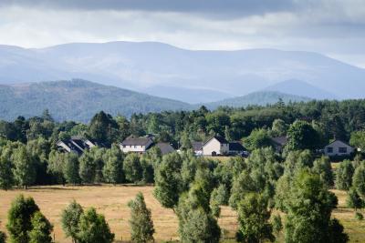 Dulnain Bridge with fields in the foreground and mountains in the background.